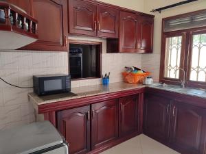 a kitchen with wooden cabinets and a microwave at HEDGE GUEST HOUSE in Kampala