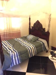 Schlafzimmer mit einem Bett mit einem Kopfteil aus Holz in der Unterkunft HEDGE GUEST HOUSE in Kampala