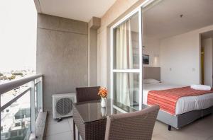 um quarto com uma varanda com uma cama e uma mesa em Flat 804 - Conforto, praticidade e vista panorâmica em Macaé em Macaé