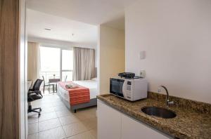 a hotel room with a bed and a kitchen with a sink at Flat 804 - Conforto e vista panorâmica em Macaé in Macaé
