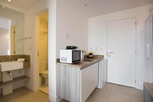 uma cozinha branca com um micro-ondas no balcão em Flat 804 - Conforto e vista panorâmica em Macaé em Macaé