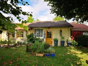 a house with a yellow door and some plants in the yard at Villa le Cloky in Thomery