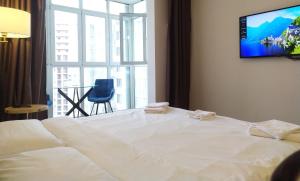 a bedroom with a large white bed with a tv on the wall at Art Hotel in Pykhtino