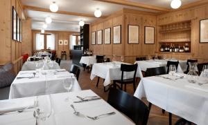 un ristorante con tavoli e sedie bianchi e pareti in legno di Pensiun Aldier a Sent