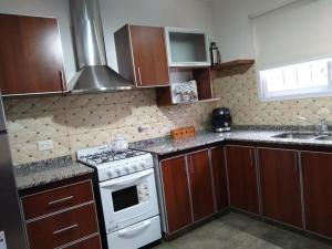 a kitchen with wooden cabinets and a white stove top oven at Casa Centrica Lujan Planta Alta in Luján