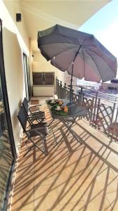d'une terrasse avec une table et un parasol sur le balcon. dans l'établissement POTATO BEACH apartment at beach front & sea view, à Lagos