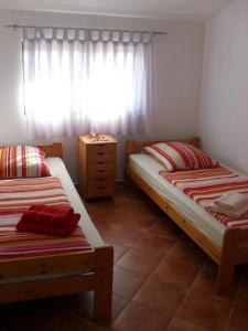 two beds in a small room with a window at Apartments Miljak in Fažana