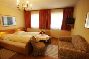 ein Hotelzimmer mit einem Bett, einem Tisch und einem Sofa in der Unterkunft Gasthof zur Post in Strasswalchen