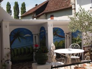 a patio with a table and a mural on the side of a house at Hotel Au Petit Béarn in Salies-de-Béarn