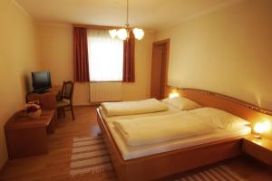 a bedroom with a bed and a desk and a television at Gasthof zur Post in Strasswalchen