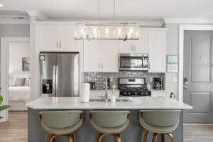 uma cozinha com armários brancos e uma ilha de cozinha com bancos em The Santee Suite at 122 Spring em Charleston
