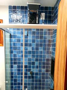 a blue tiled bathroom with a shower with at Chalé Vera Ar condicionado Pousada 35knots Brasil in Luis Correia
