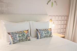 a white bed with two pillows and a white headboard at Mouraria Lisboa Hotel in Lisbon
