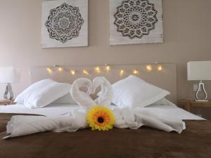 een bed met witte handdoeken en een bloem erop bij Sweet Dreams Tenerife Las Américas in Playa Fañabe