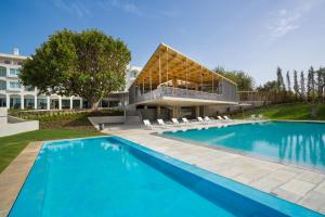 a swimming pool in front of a house with a building at OZADI Tavira Hotel in Tavira