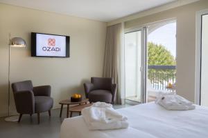 Habitación de hotel con 1 cama y 2 sillas en OZADI Tavira Hotel, en Tavira