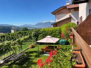 einen Garten mit einem Tisch und einem Regenschirm und ein paar Blumen in der Unterkunft Agriturismo La Canonica in Brez