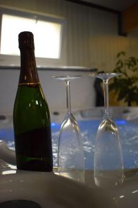- deux verres à vin et une bouteille sur une table dans l'établissement Gite 5 pers avec 2h espace bien-être privatisé inclus dans le prix de la nuit 80m2 de détente, à Équilly