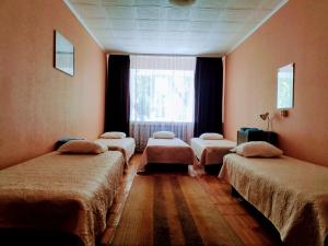 a room with four beds and a window at White House in Uulu