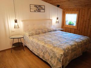 Lozzo CadoreにあるLa Mansardaのベッドルーム1室(ベッド1台、テーブル2台、窓付)
