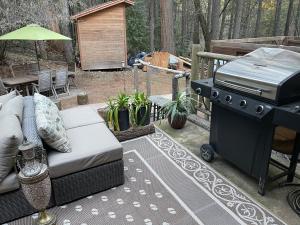 a grill and a couch sitting on a patio at A Lovely Cabin House at Way Woods Retreat with Outdoor Hot Tub! - By Sacred Hub MGMT in Foresthill