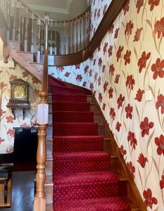 a staircase leading up to a large room with red walls at Greenfields Country House in Latton