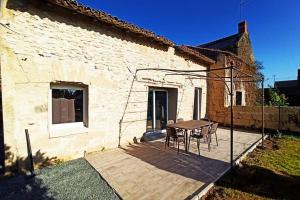 a patio with a table and chairs next to a building at Petite maison de charme in Doué-la-Fontaine
