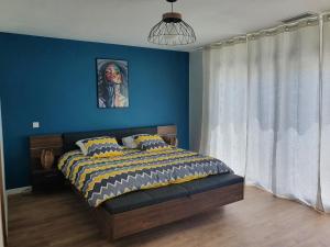 1 dormitorio con 1 cama con pared azul en La suite de la route des chateaux, en Arsac