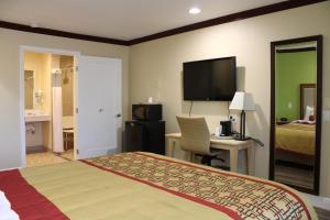 a hotel room with a bed and a desk and a television at Imperial Inn Oakland in Oakland