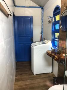 baño con lavabo blanco y puerta azul en Chalés no centro de Bombinhas, en Bombinhas