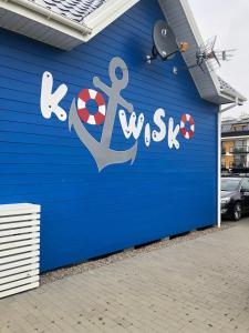 a blue building with an anchor painted on it at Kotwisko in Sarbinowo