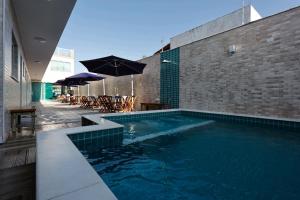 una piscina con mesas y sombrillas junto a un edificio en Pousada Peruibiza, en Peruíbe