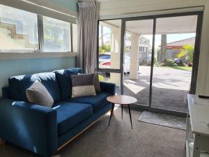 uma sala de estar com um sofá azul e uma mesa em Peaceful Mount Studio Moments to Beach & Downtown em Mount Maunganui