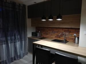 a kitchen with a sink and a counter with chairs at Czerwona Cegła Apartament in Zielona Góra