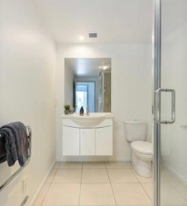 a white bathroom with a sink and a toilet at Modern Beach Apartment with Pool & Location in Mount Maunganui