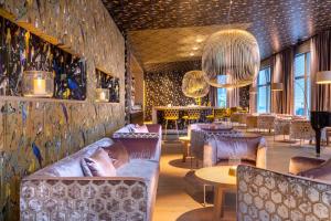 un ristorante con divani, tavoli e lampadario a braccio di Dolomitengolf Suites a Lavant