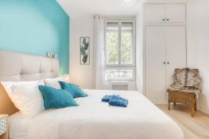 a bedroom with a large white bed with blue pillows at Superbe appartement tout près de Paris in Alfortville