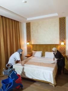 Palm’s Motel في أغادير: شخصان يرتبان سرير في غرفة في الفندق