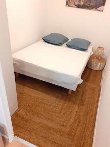 1 cama con sábanas blancas y almohadas azules en una habitación en Aubagne Centre ancien avec place de STATIONNEMENT et wifi gratuit inclus, en Aubagne