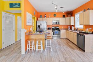 a kitchen with orange walls and white cabinets and bar stools at The Lucky Beach House, The Most Popular Beach House in Atlantic City! WOW! in Atlantic City