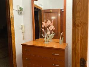 un tocador con espejo y un jarrón con flores. en Apartamento de 1 dormitorio en buena ubicación en Albacete