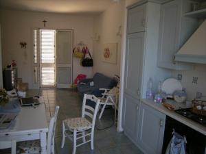 cocina con armarios blancos, mesa y sillas en Casuzze Country, en Marina di Ragusa
