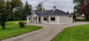 a small white house with a gravel driveway at Rossgier bungalow in Lifford