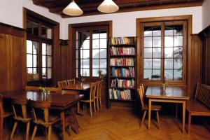 uma biblioteca com duas mesas e uma estante de livros com livros em Leissigen Youth Hostel em Leissigen