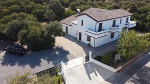 un'auto parcheggiata di fronte a una casa bianca di B&B Juniperus a SantʼAnna Arresi