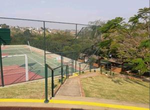 una pista de tenis con valla y pistas de tenis en Flat encantador localizado no melhor de Serra Negra - SP en Serra Negra