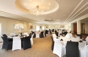 a banquet hall with white tables and black chairs at Gold Reef City Theme Park Hotel in Johannesburg