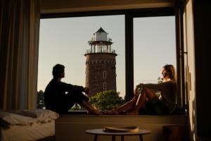 mężczyzna i kobieta siedzący w oknie z latarnią morską w obiekcie Apartamenty z widokiem na morze i dziedziniec, parking BalticON Morska 6 w Kołobrzegu