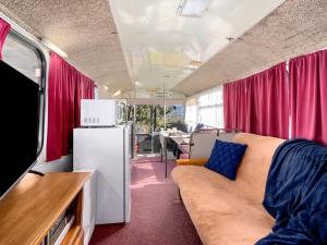 The Old School Bus في Bilpin: غرفة معيشة مع أريكة وثلاجة