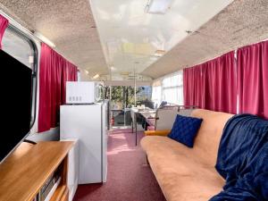 a living room with a couch and a refrigerator at The Old School Bus in Bilpin